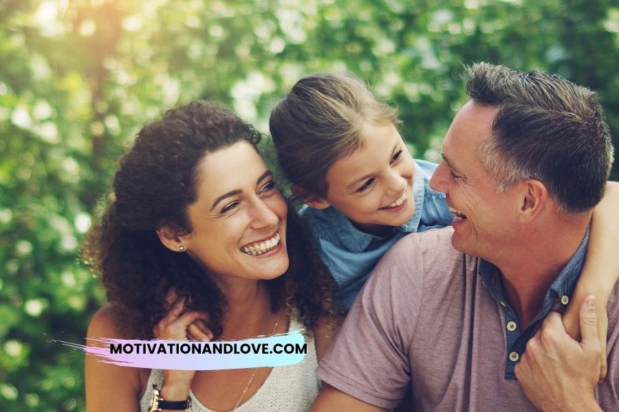 A smiling family poses outdoors with green background.