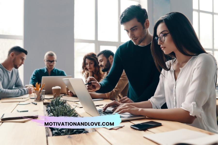 People working at a long table with laptops and office supplies.