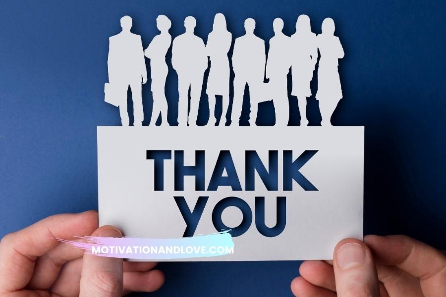 A greeting card with the words "THANK YOU" cut out is being held by two hands against a blue background; the top edge of the card is adorned with silhouetted figures.